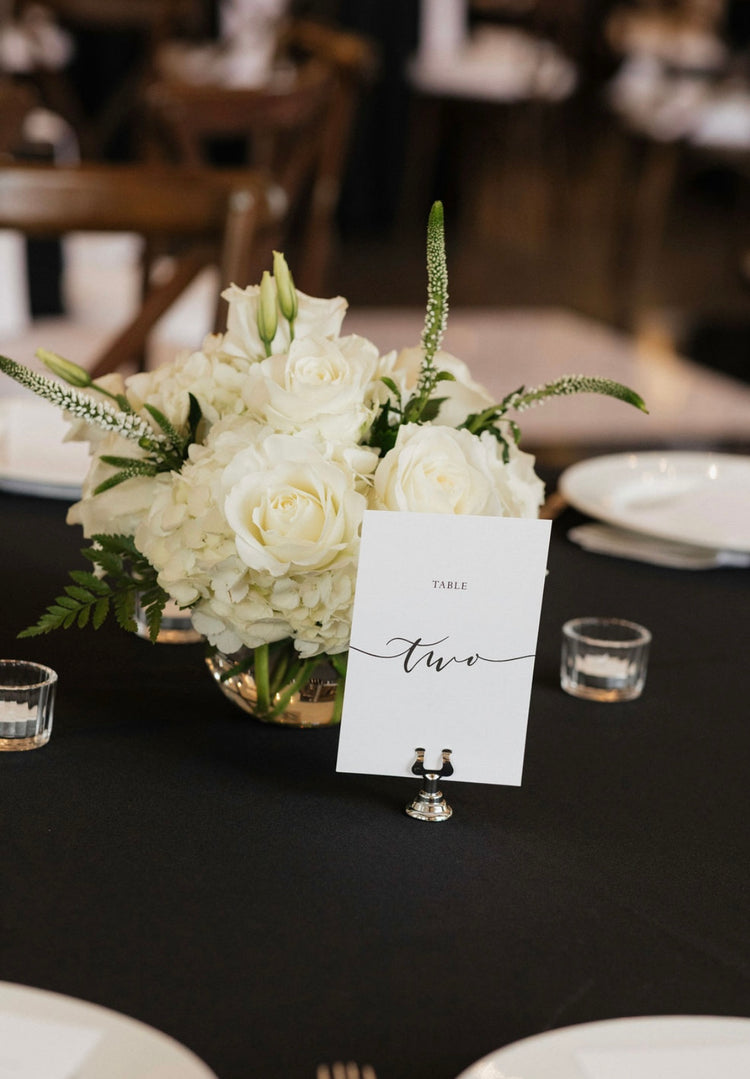 Low white rose and hydrangea centerpiece with veronica on a black reception table