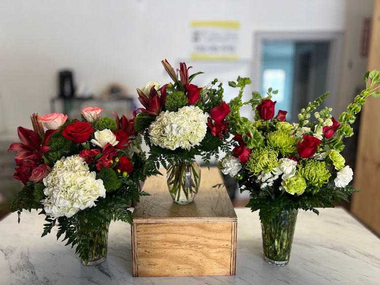 Soft pink roses, white stock, and green button mums in a vase on a metal stand