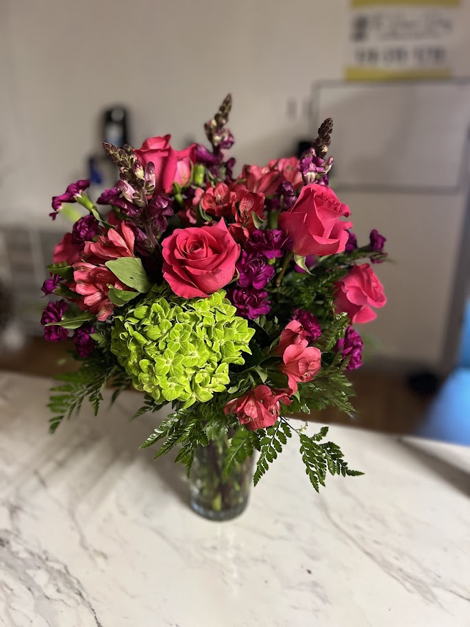 Hot pink roses and purple stock around bright green hydrangea