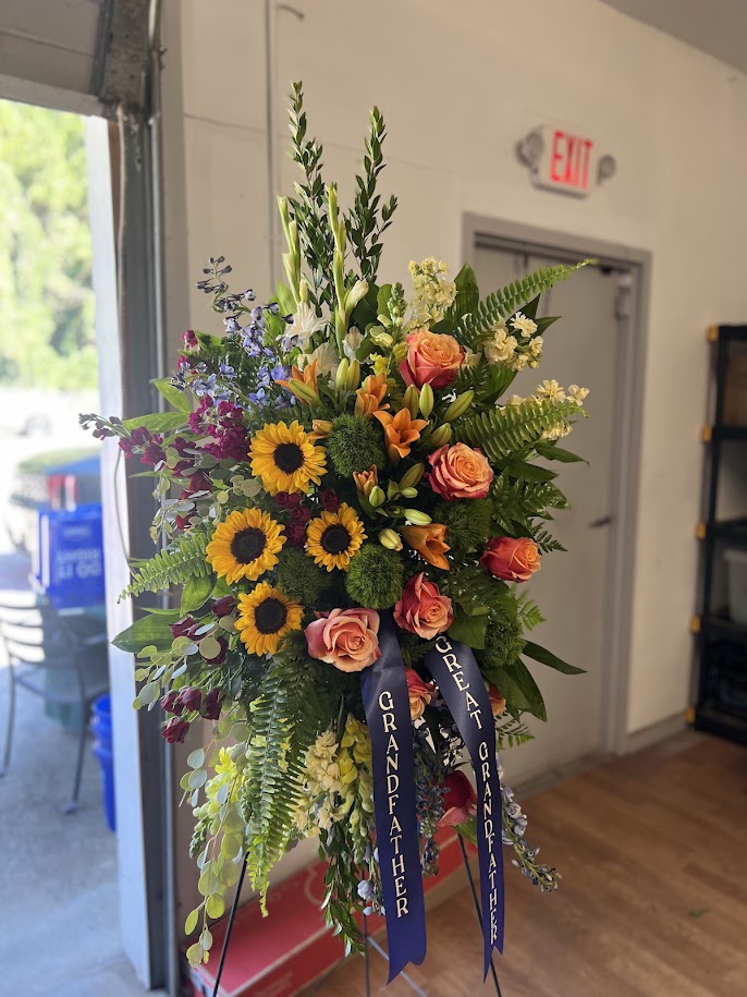 Standing spray of sunflowers and peach roses with a Great Grandfather ribbon