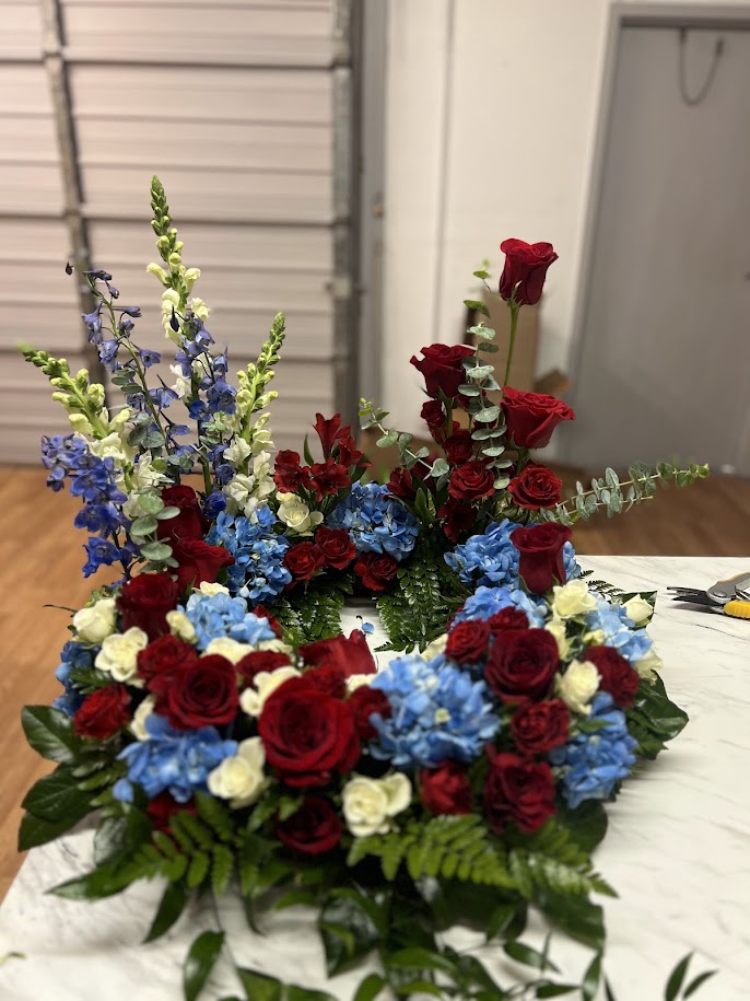 Red, white, and blue tribute of roses, hydrangea, delphinium, and snapdragons