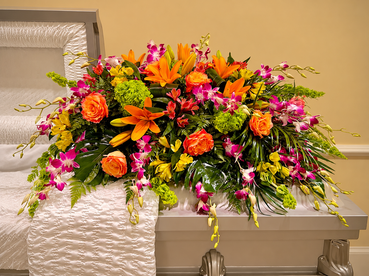 Bright casket spray of orange roses, lilies, and pink orchids